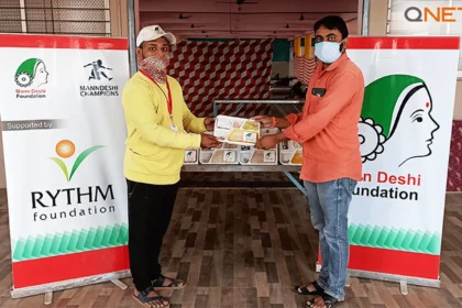 A representative from Mann Deshi Foundation providing meals to a beneficiary as a part of the COVID relief provided by QNET