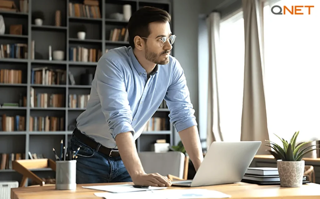 An ambitious entrepreneur looking outside the window at his home while working