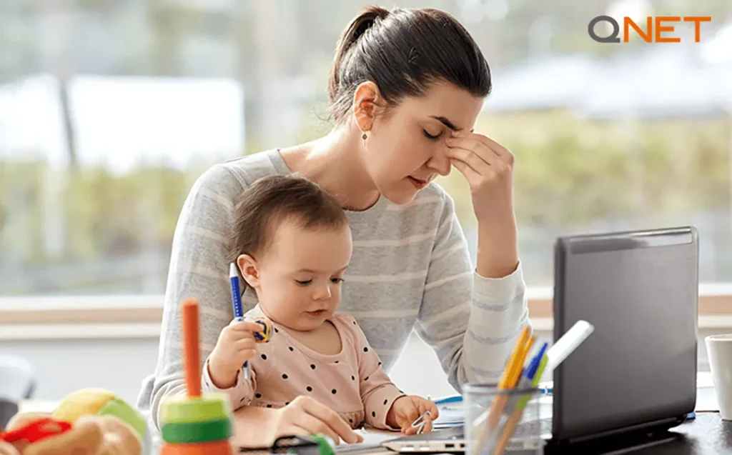 A stressed working Mompreneur working on a laptop beside her children